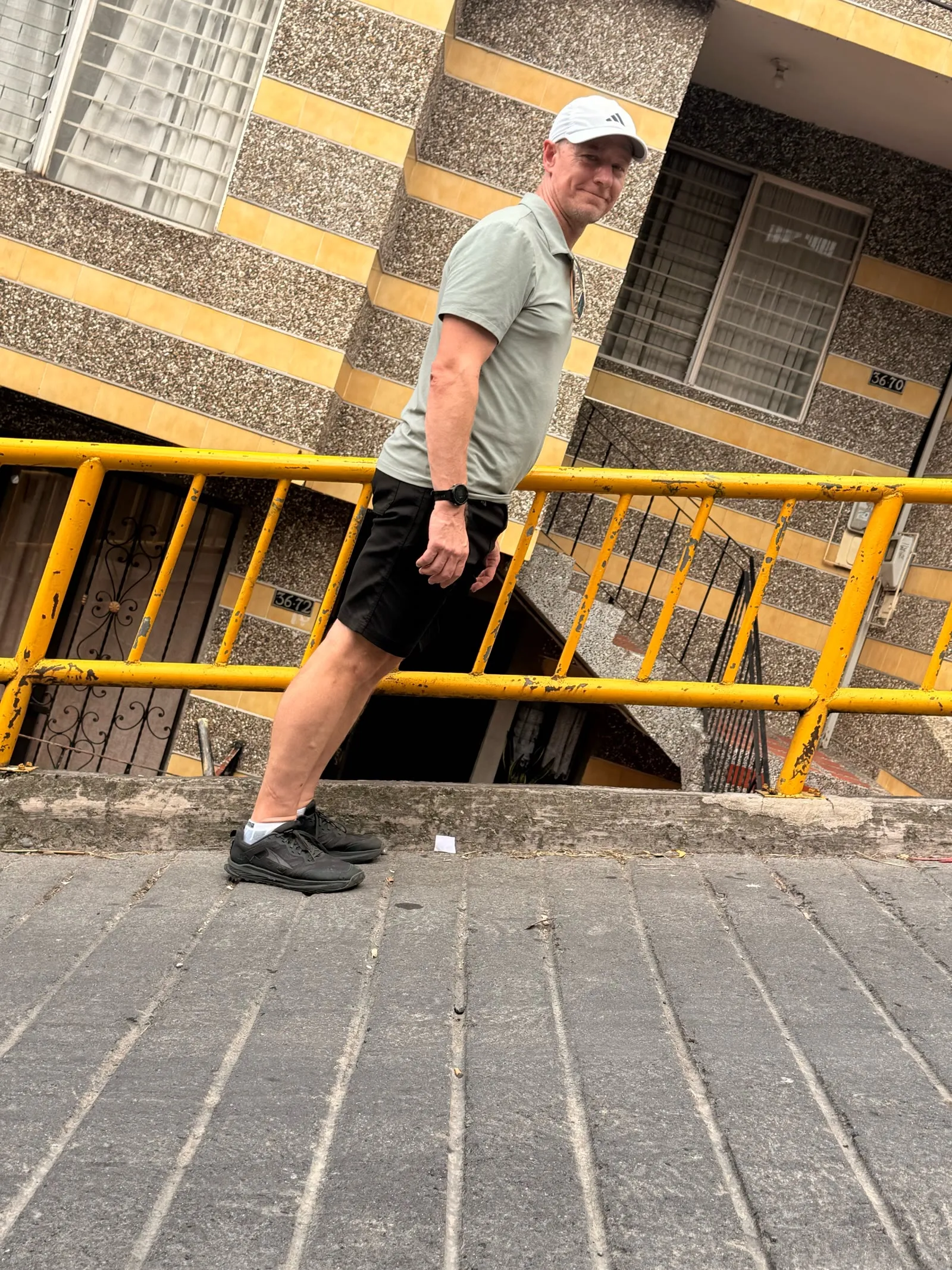 Me leaning into one of Medellín's steep hillside streets, next to a yellow railing.