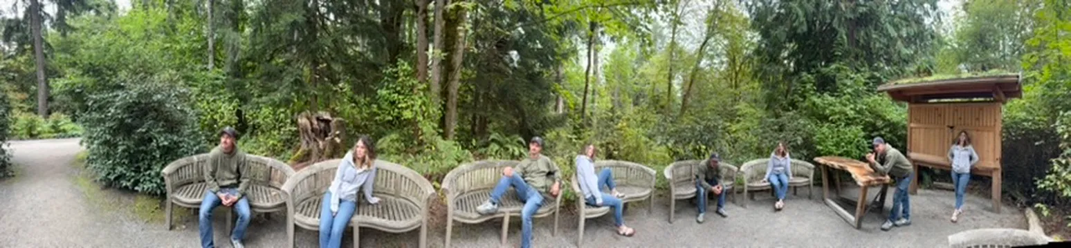 A panorama of the family on wooden benches along a forest path, with the same people showing up in several spots across the picture.